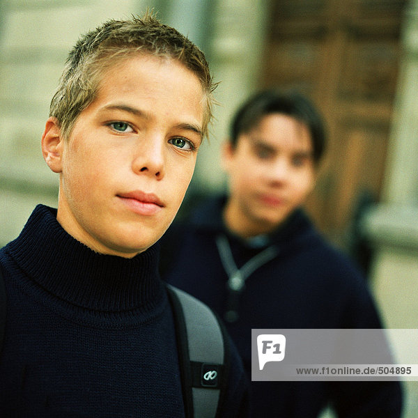 Teenager-Junge schaut in die Kamera,  zweiter Teenager im Hintergrund