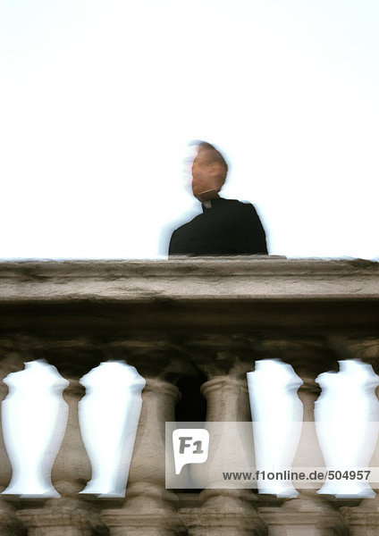 Priest standing behind rail  low angle view  blurred