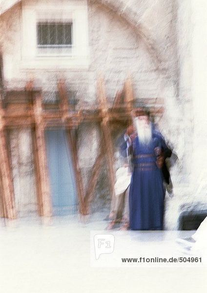 Orthodox priest standing in front of old edifice  blurred