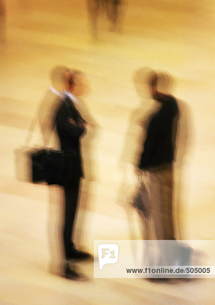 Two men standing in concourse  blurred