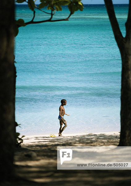 Junge geht am Strand spazieren,  Meer im Hintergrund