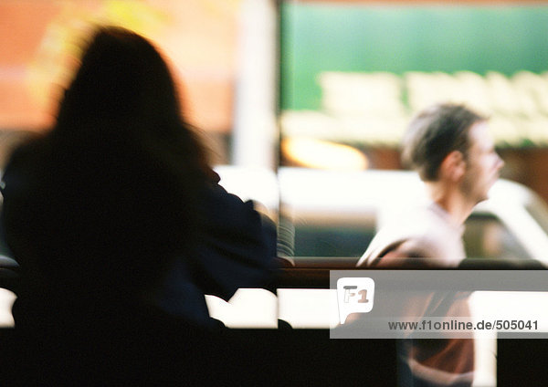 Silhouette of woman sitting  man walking in background  blurred