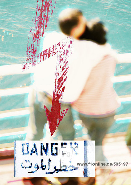 Paar an der Schiene stehend mit rotem Pfeil  arabischem Text und ''Gefahr'' Text  Montage  Nahaufnahme''.