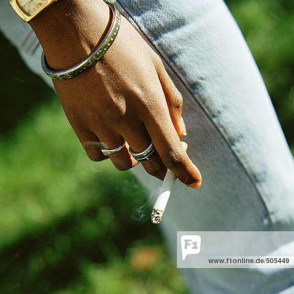 Hand der jungen Frau mit angezündeter Zigarette,  Nahaufnahme