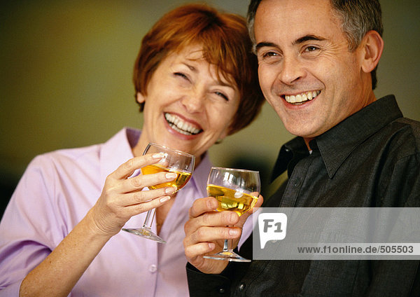 Man and woman smiling and holding up wine glasses  close up