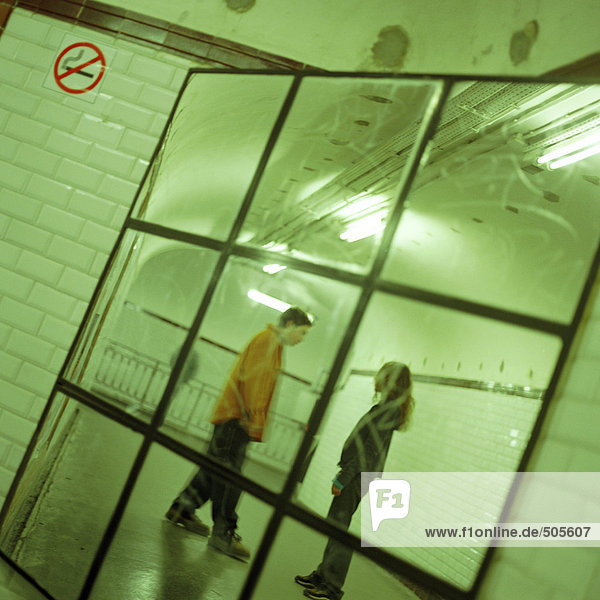 Junge Leute  die sich im U-Bahn-Stationskorridor unterhalten  im Spiegel betrachtet.