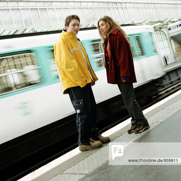 Young people standing on platform  in front of moving subway train  blurred
