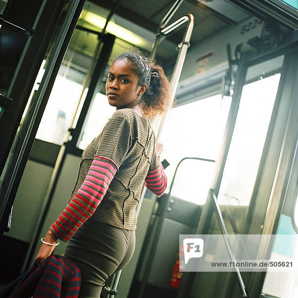 Junge Frau hält die Reling  steigt in den Bus  blickt zurück über die Schulter