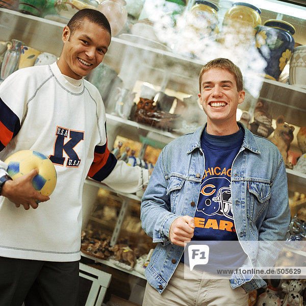 Young men leaning against store window  smiling  facing camera.