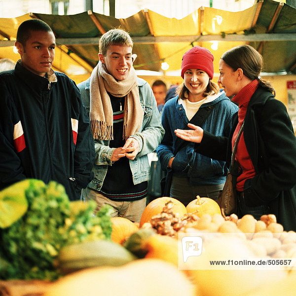 Young people at produce market  fruits and vegetables blurred in foreground