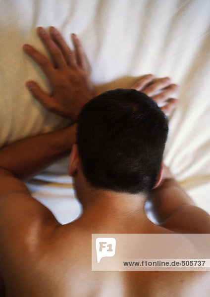 Mann mit dem Gesicht nach unten auf dem Bett liegend  mit Kopf auf den Händen  verschwommen  hoher Blickwinkel
