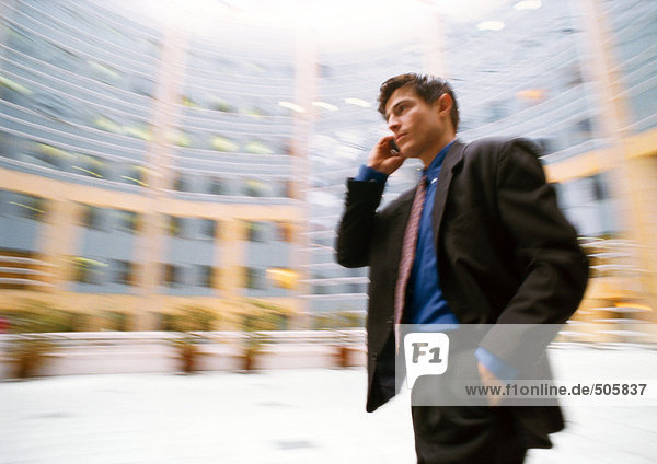 Businessman talking on cell phone  outside  building in background  blurred.