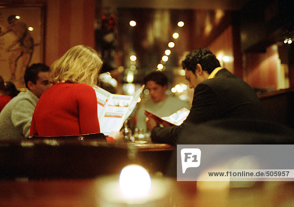 Group of young people sitting in restaurant looking at menus