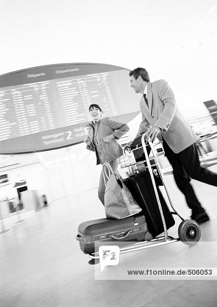 Geschäftsmann und Geschäftsfrau  die durch das Flughafenterminal laufen  verschwommen  s/w.