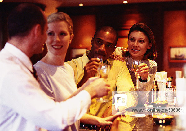 Group of business people raising glasses at bar