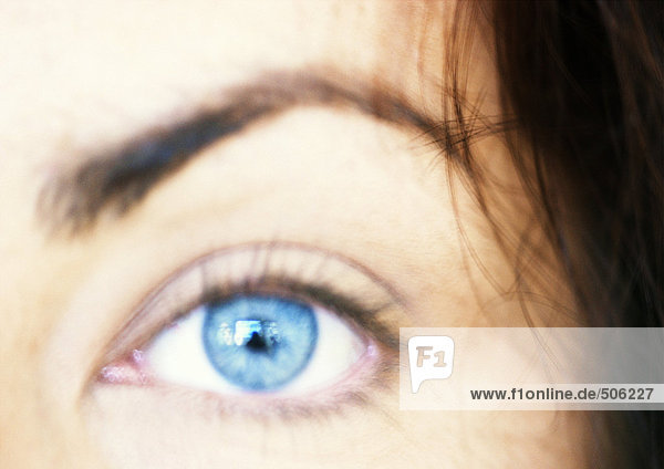 Blaues Auge der Frau  Augenbraue hochgezogen  verschwommene Nahaufnahme.
