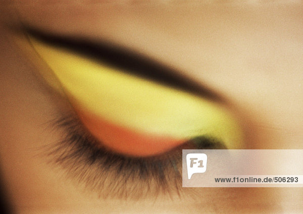 Geschlossenes Auge der Frau mit gelbem und orangem Lidschatten,  Nahaufnahme