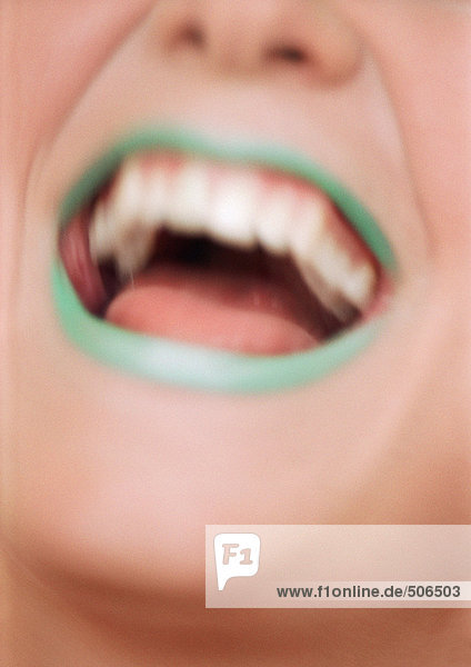 Nahaufnahme des Frauenmundes offen und lächelnd mit grünem Lippenstift  verschwommen