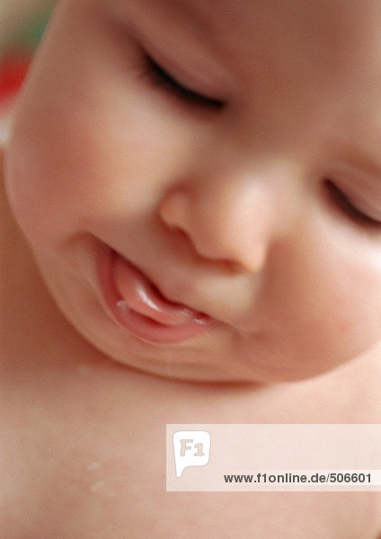 Baby mit geschlossenen Augen  herausstehende Zunge  Nahaufnahme.