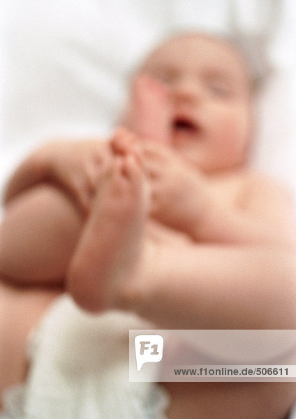 Baby lying on back  holding feet  blurred
