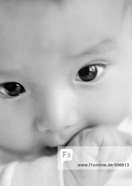 Baby's face with hand in mouth  close-up  B&W.