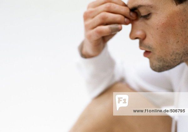 Mann hält Nasenrücken mit Fingern  Seitenansicht  Nahaufnahme