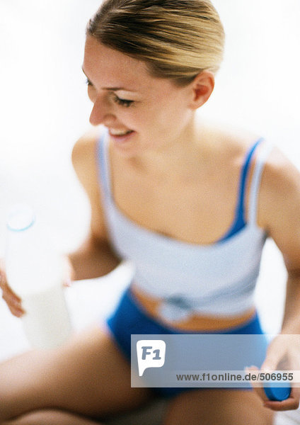 Woman in workout clothes holding bottle  smiling  high angle view