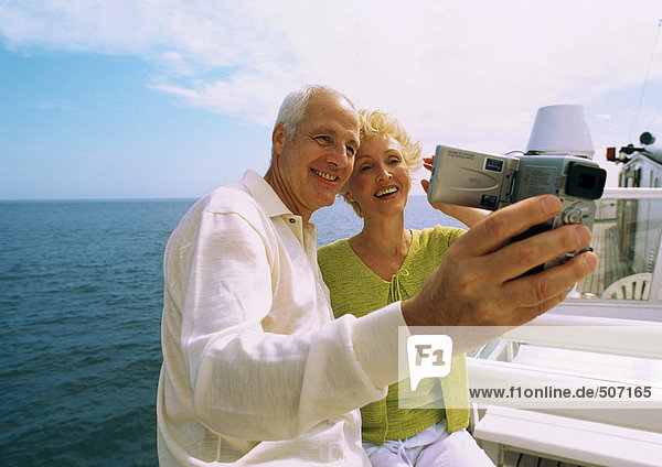 Mature couple making video of themselves on boat