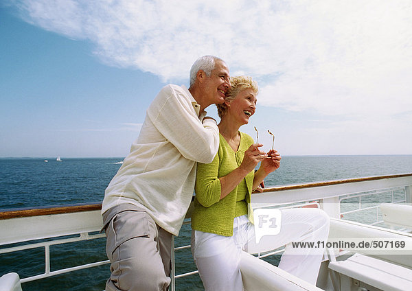 Mature couple leaning against railing  smiling
