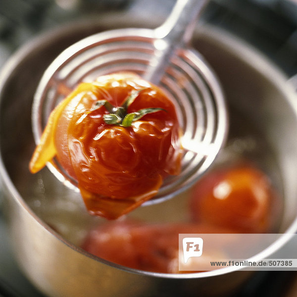 Nahaufnahme der gekochten Tomate auf dem Skimmer über dem Topf