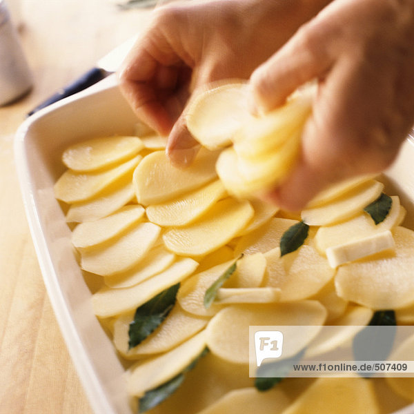 Nahaufnahme der Hände bei der Zubereitung von überbackenen Kartoffeln