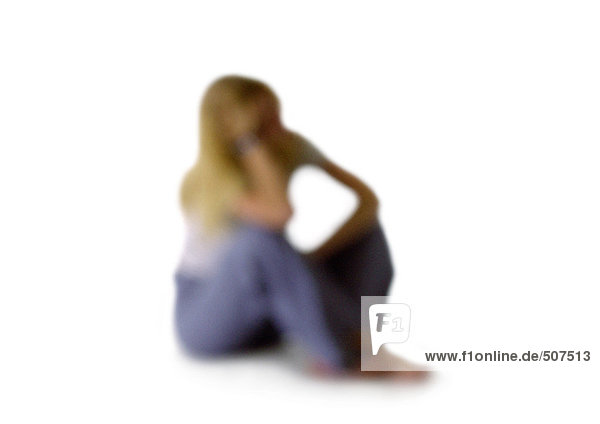 Silhouette der Frau sitzend mit hochgezogenen Knien  an den Ellenbogen gelehnt  auf weißem Hintergrund  defokussiert