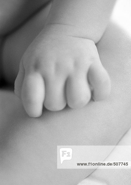 Baby's hand on leg  close-up  b&w