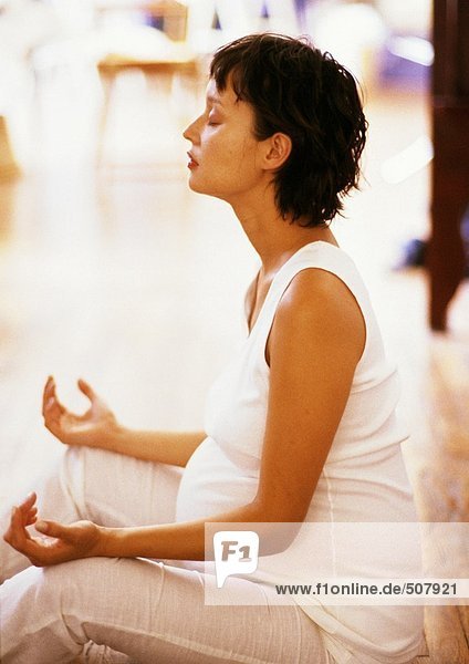 Schwangere sitzend in Meditationsstellung  Seitenansicht