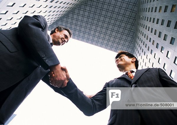 Zwei Geschäftsleute beim Händeschütteln  Blick in den niedrigen Winkel