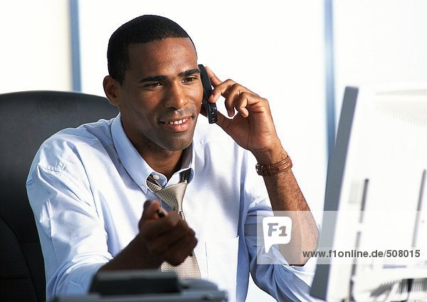 Businessman sitting at desk  using telephone