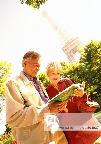 Frankreich  Paris  reife Frau und Mann untersuchen ein Buch  Eiffelturm im Hintergrund
