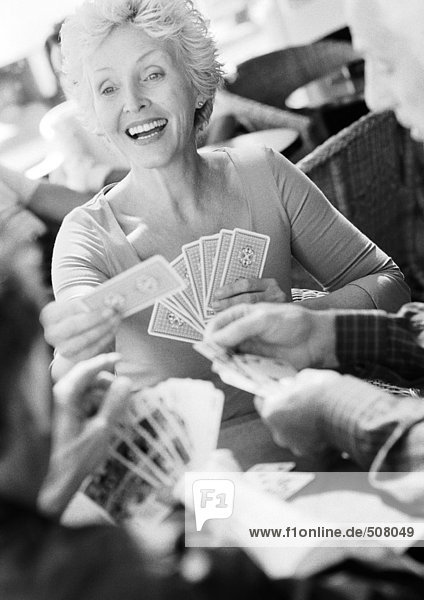 Reife Frau spielt Karten  verschwommener Vordergrund  S/W