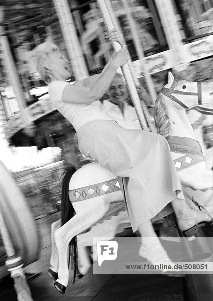 Mature woman laughing on a carousel  B&W