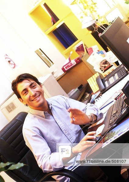 Man working at desk in office  smiling at camera