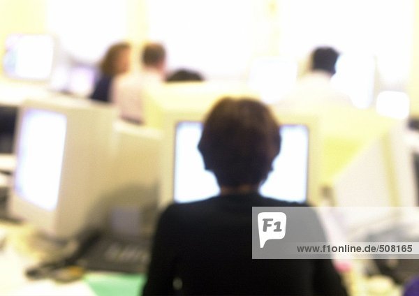 Woman working at computer in office  blurred  rear view