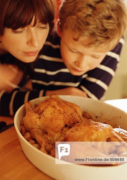 Frau und Kind betrachten Hühner in der Auflaufform