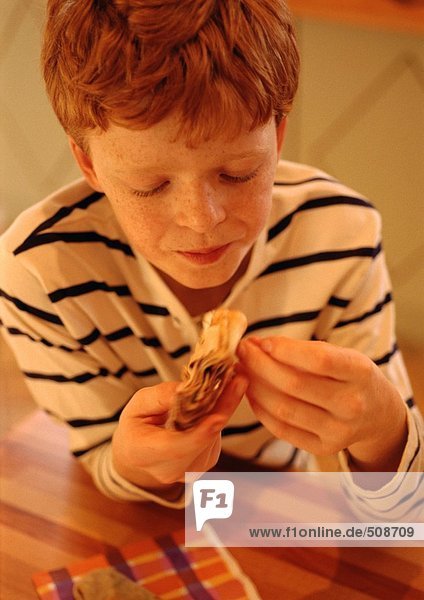 Kind hält Essen in den Händen  schaut nach unten  Porträt