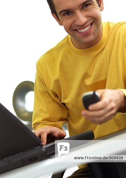 Mann mit Laptop und Handy  lächelnd