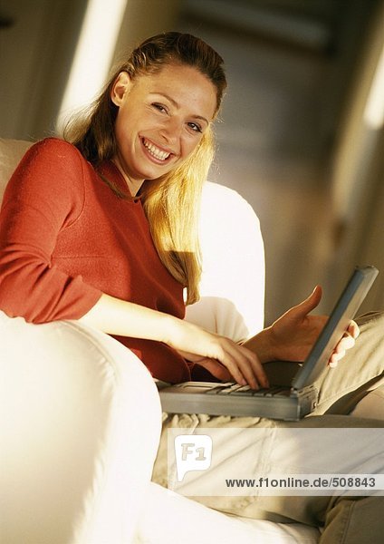 Woman holding laptop computer on knees  portrait