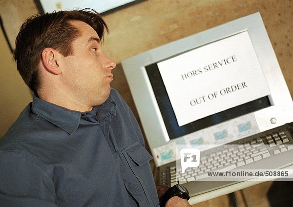 'Man looking at computer screen with ''out of order'' sign on screen'