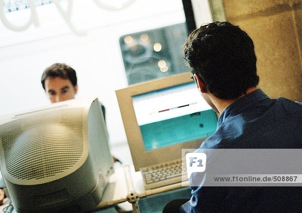 Zwei Männer  die an Computern im Cyber-Café arbeiten.