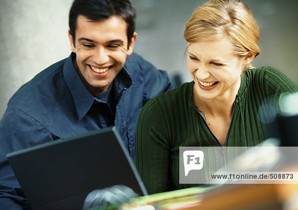 Businessman and woman with laptop computer  smiling