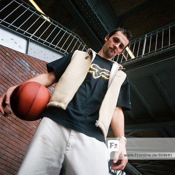 Young man holding basketball  low angle view