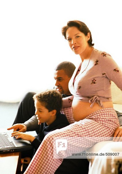 Schwangere Frau sitzend mit Mann und Kind  Kind mit Laptop-Computer